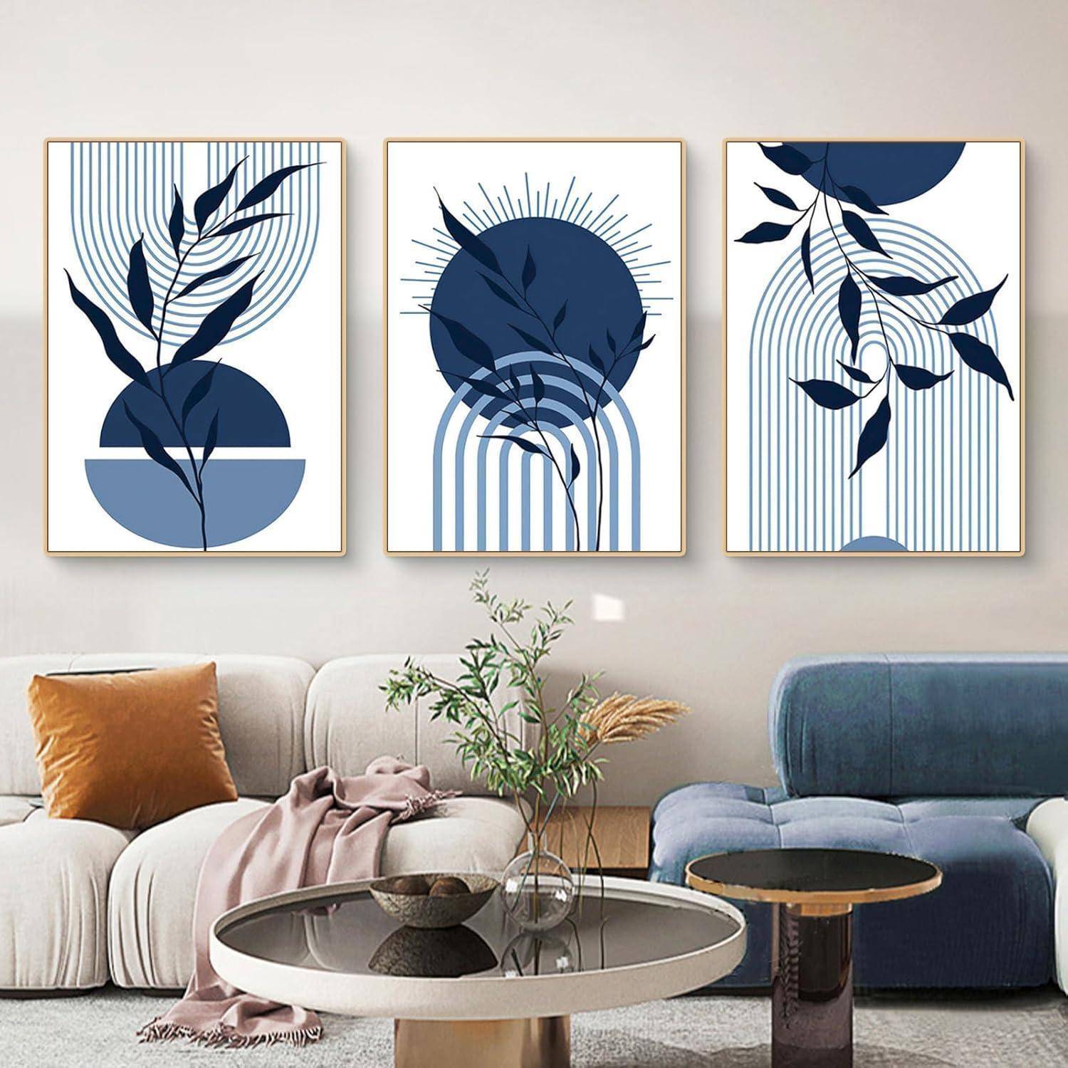Drei abstrakte Kunstwerke mit marineblauem Laub und geometrischen Formen hängen über einem modernen Sofa und schaffen einen stilvollen Blickfang.