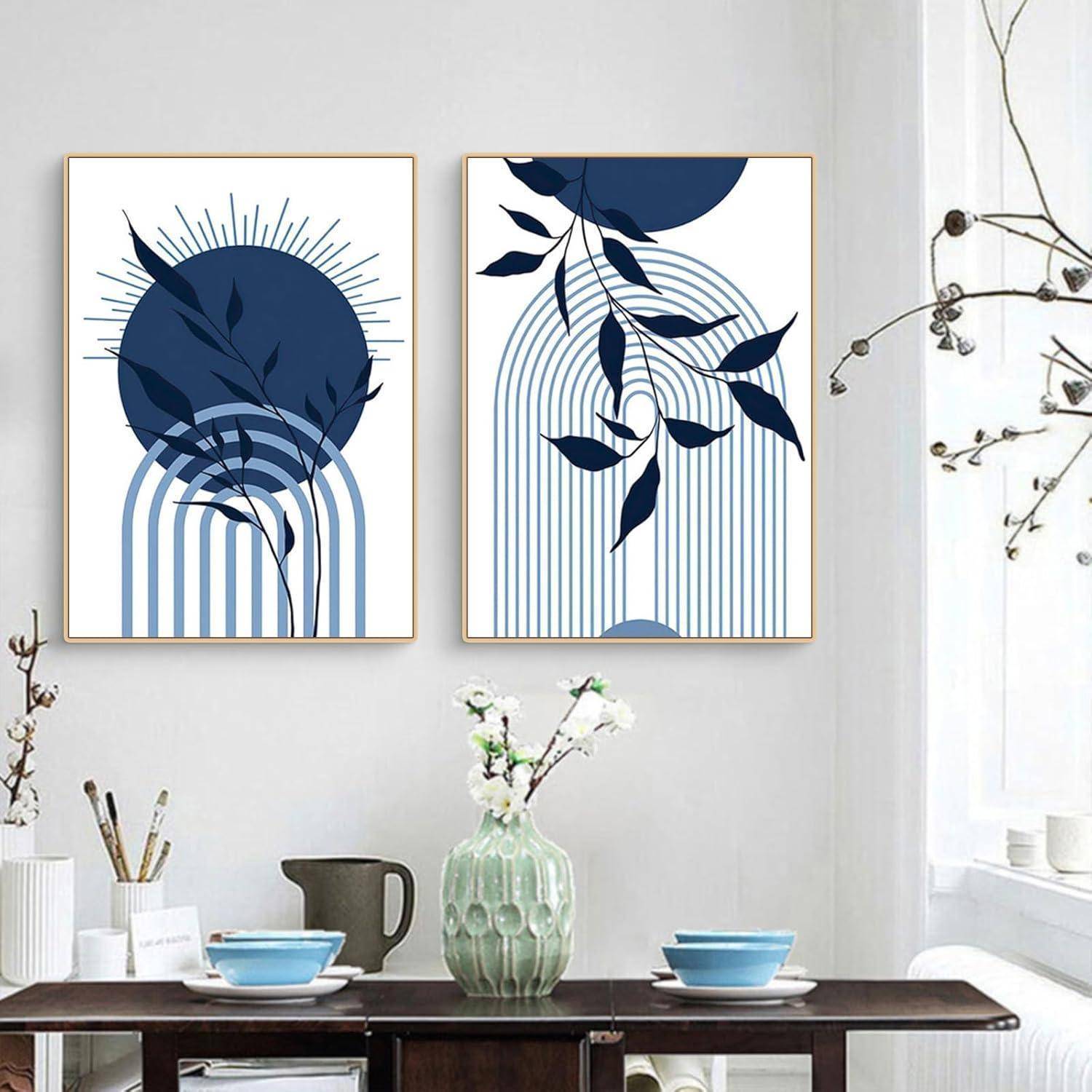 Zwei gerahmte abstrakte Kunstwerke mit blauen Formen, Blättern und Linien hängen an einer weißen Wand über einem Regal mit Vasen und Büchern.