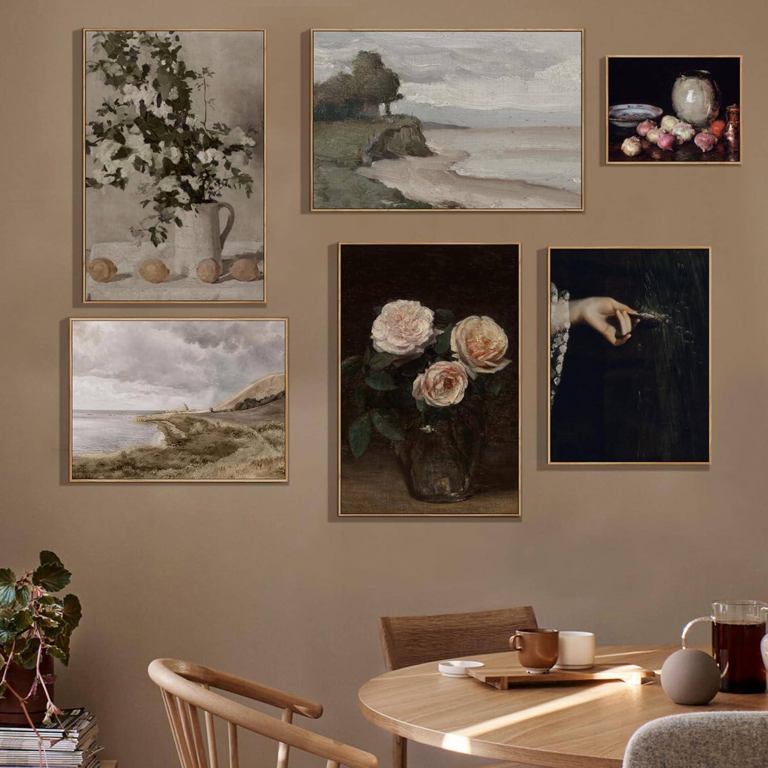 An der Wand hängen gerahmte Kunstwerke: Blumenstillleben, Landschaften und Früchte. Darunter steht auf einem Holztisch eine Tasse und eine kleine Vase. Gemütliche Atmosphäre.