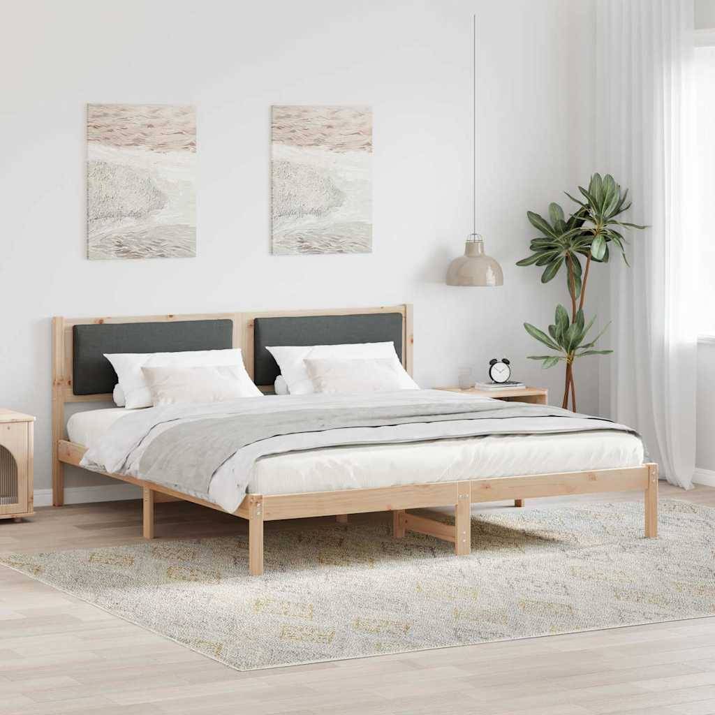 Ein minimalistisches Schlafzimmer zeigt ein Holzbett mit grauen Bettwäsche, zwei naturthematischen Gemälden darüber und eine Topfpflanze neben einer Lampe auf der rechten Seite.