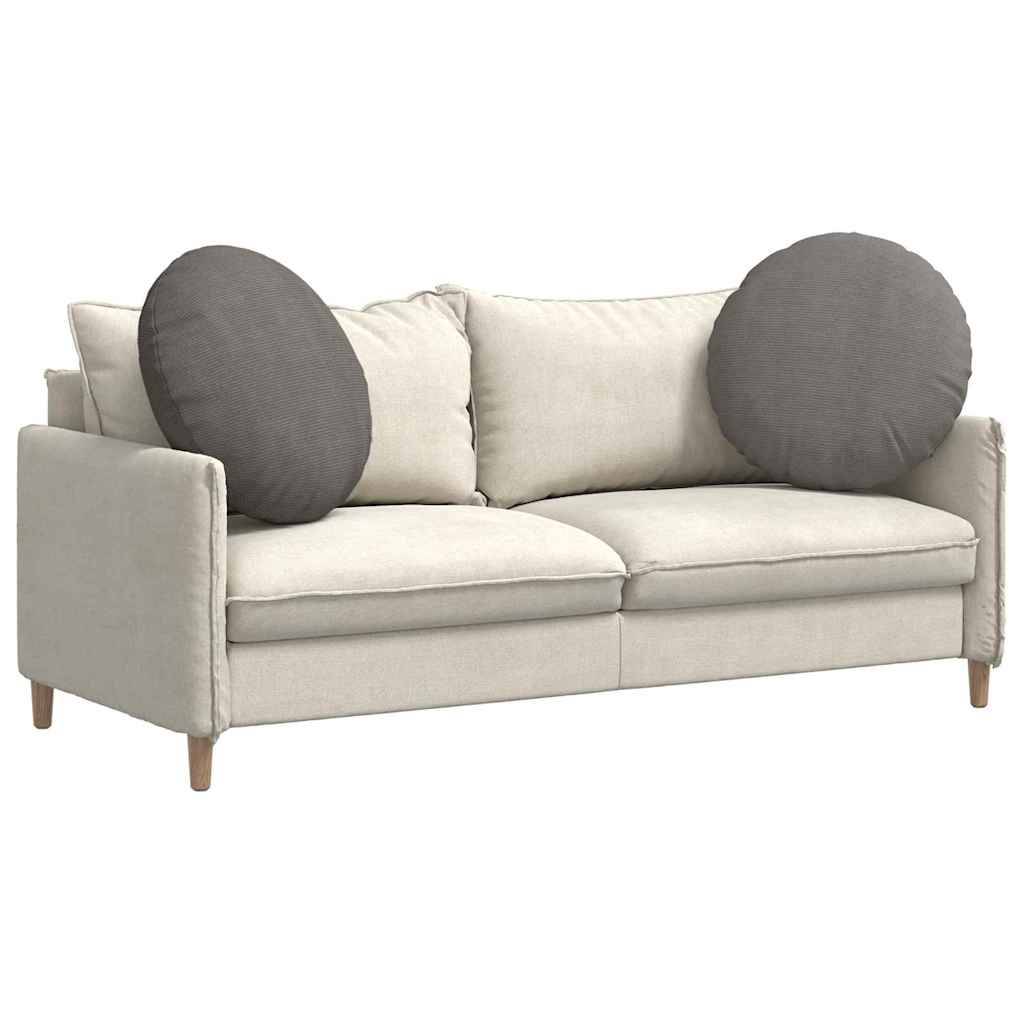 Eine cremefarbene, moderne Couch mit Holzbeinen und zwei großen, runden, grauen Kissen, die an jedem Ende platziert sind.