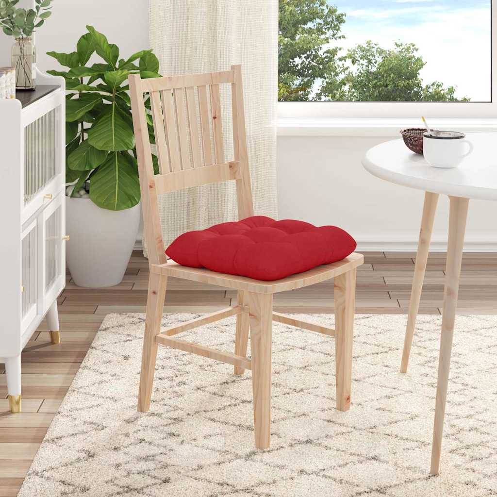 Ein gemütliches Zimmer mit einem Holzstuhl und einem roten Kissen neben einem kleinen Tisch, eine Pflanze auf einem Schrank und ein Fenster, das einen klaren blauen Himmel zeigt.