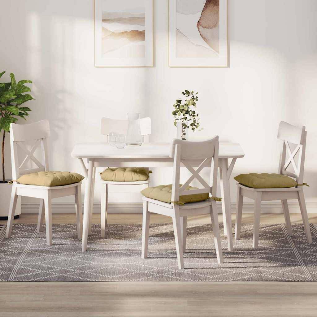 Ein heller Essbereich mit einem weißen Tisch, vier Stühlen mit grünen Kissen und zwei abstrakten Gemälden an der Wand. Natürliches Licht durchflutet den Raum.