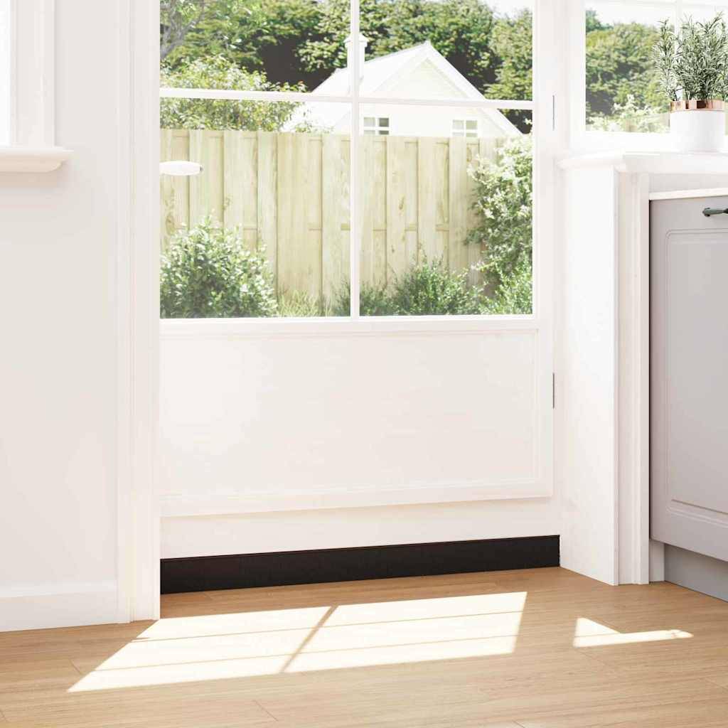 Sonnendurchflutete Raumecke mit einem großen Fenster, das grüne Bäume und einen Holzzaun im Außenbereich zeigt. Eine Zimmerpflanze auf einem Sims, Hellholzdielen auf dem Boden.