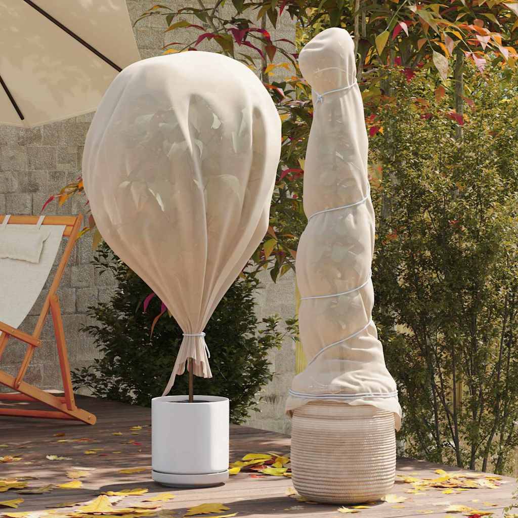 Eine Terrasse zeigt zwei überdachte Skulpturen; eine ähnelt einer birnenförmigen Gestalt, die andere ist hoch und verdreht. Sie stehen vor belaubten Bäumen.