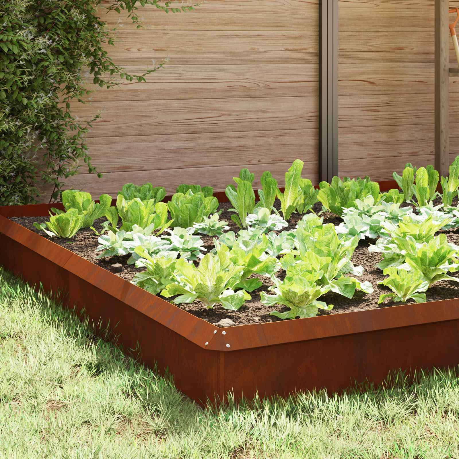 Ein erhöhtes Hochbeet mit grünem Blattgemüse befindet sich in einem gestalteten Garten neben einem Holz- und Metallzaun.