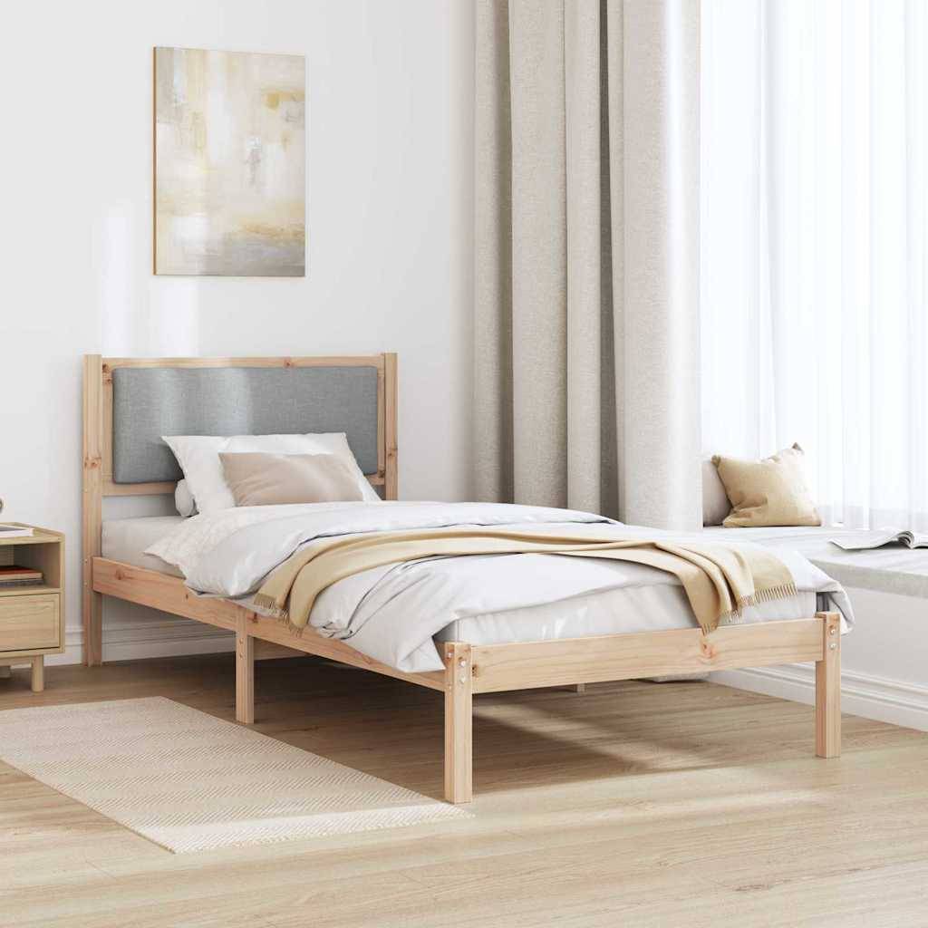 Ein modernes Schlafzimmer mit einem Bettgestell aus Holz, einem grauen Kopfteil, beigefarbener Bettwäsche und lichtdurchfluteten Vorhängen neben einem kleinen weißen Nachttisch.