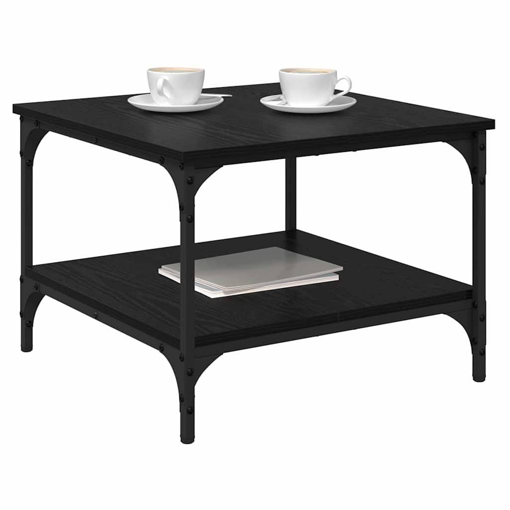 Ein schwarzer quadratischer Couchtisch mit einem Regal darunter, auf dem ein Buch liegt. Zwei weiße Teetassen auf Untertassen sind auf der Tischplatte platziert.