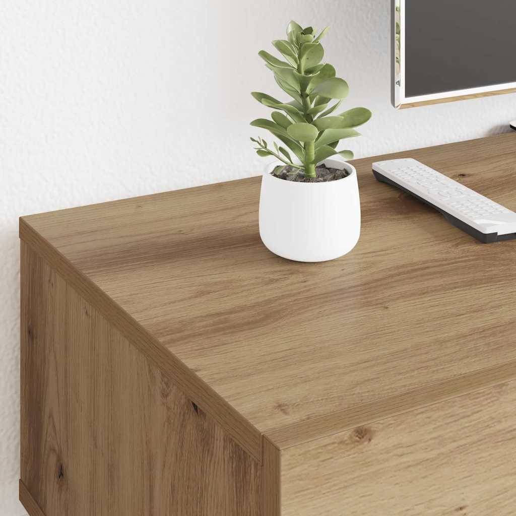 Eine kleine Topfpflanze steht auf einem Holzschreibtisch neben einer Tastatur, wobei ein Teil eines Monitors im Hintergrund zu sehen ist, was auf einen Arbeitsplatz hindeutet.