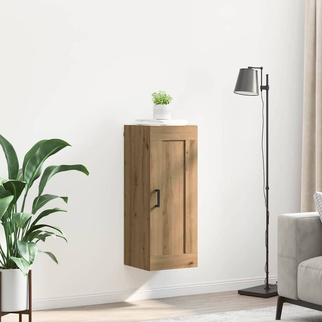 Ein kleiner, hölzerner Wandschrank mit einer Topfpflanze obenauf, neben einer schwarzen Stehlampe und einer großen grünen Blattpflanze.