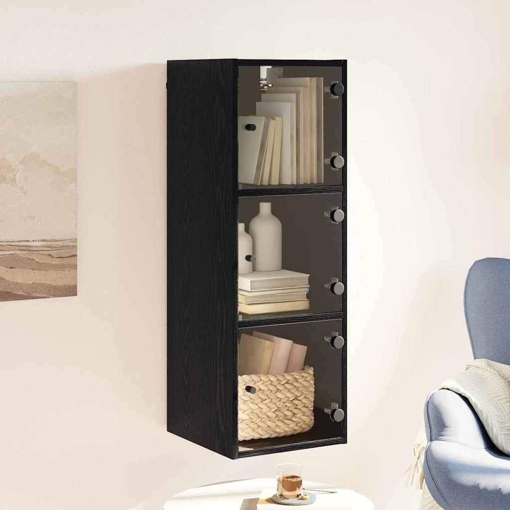 Ein schwarzer, wandmontierter Schrank mit Glastüren zeigt Bücher, eine Vase und einen geflochtenen Korb. Er befindet sich neben abstraktem Wandkunstwerk.