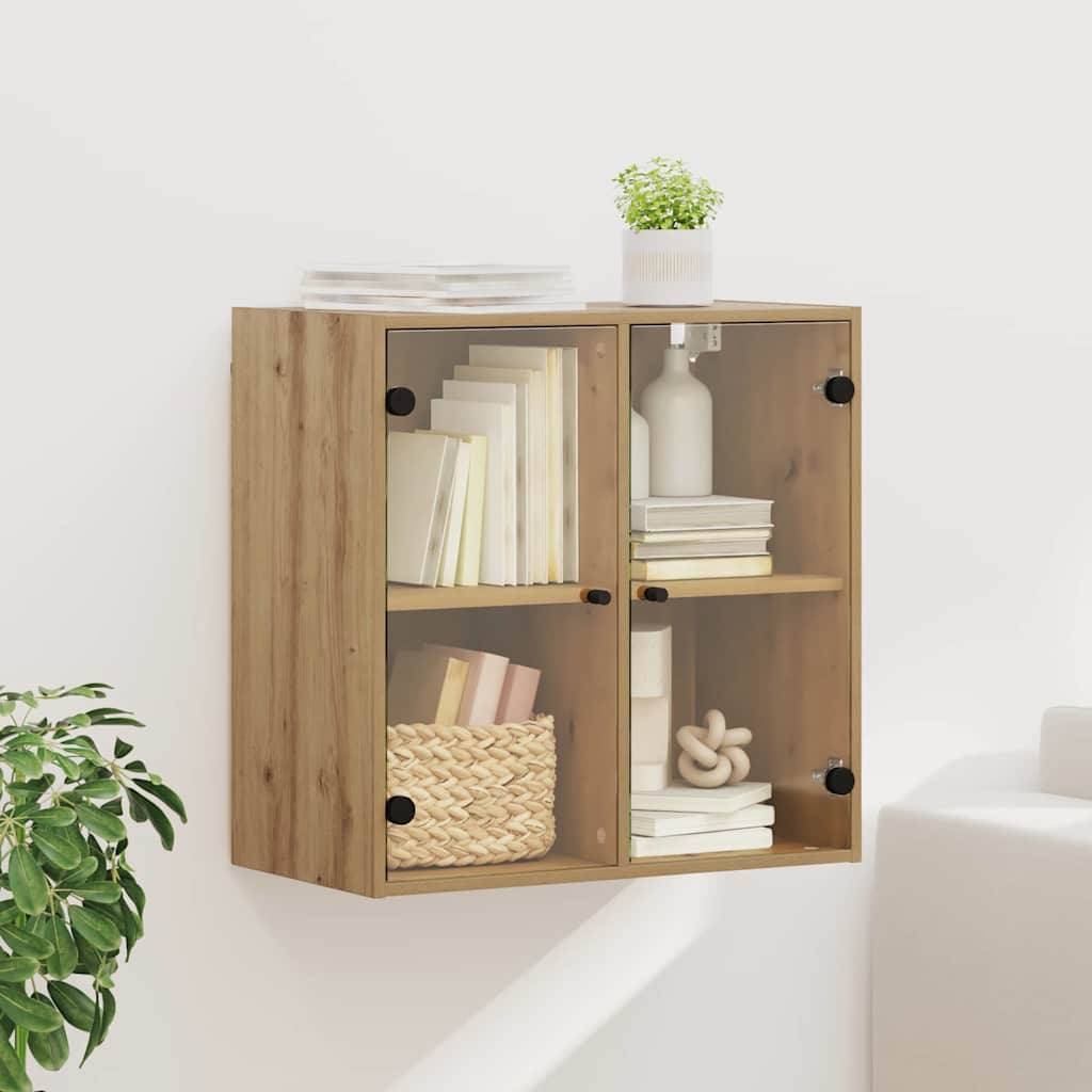 Ein Holzwandschrank mit Glastüren, in dem Bücher ausgestellt sind, ergänzt durch eine Topfpflanze, eine kleine Vase und einen geflochtenen Korb in einem hell beleuchteten Raum.