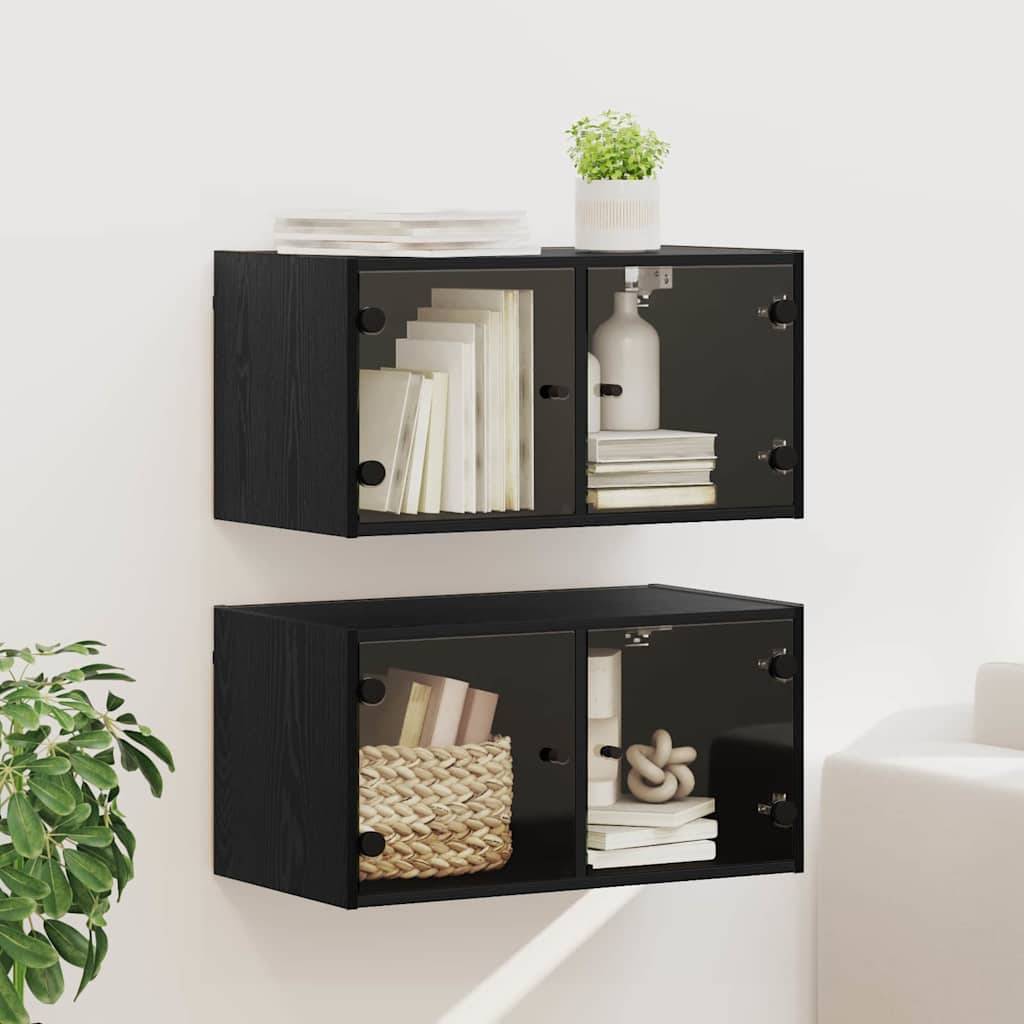 Zwei wandmontierte schwarze Stahlschränke mit Glastüren, die Bücher, eine Topfpflanze und einen Korb in einem modernen Raumambiente enthalten.