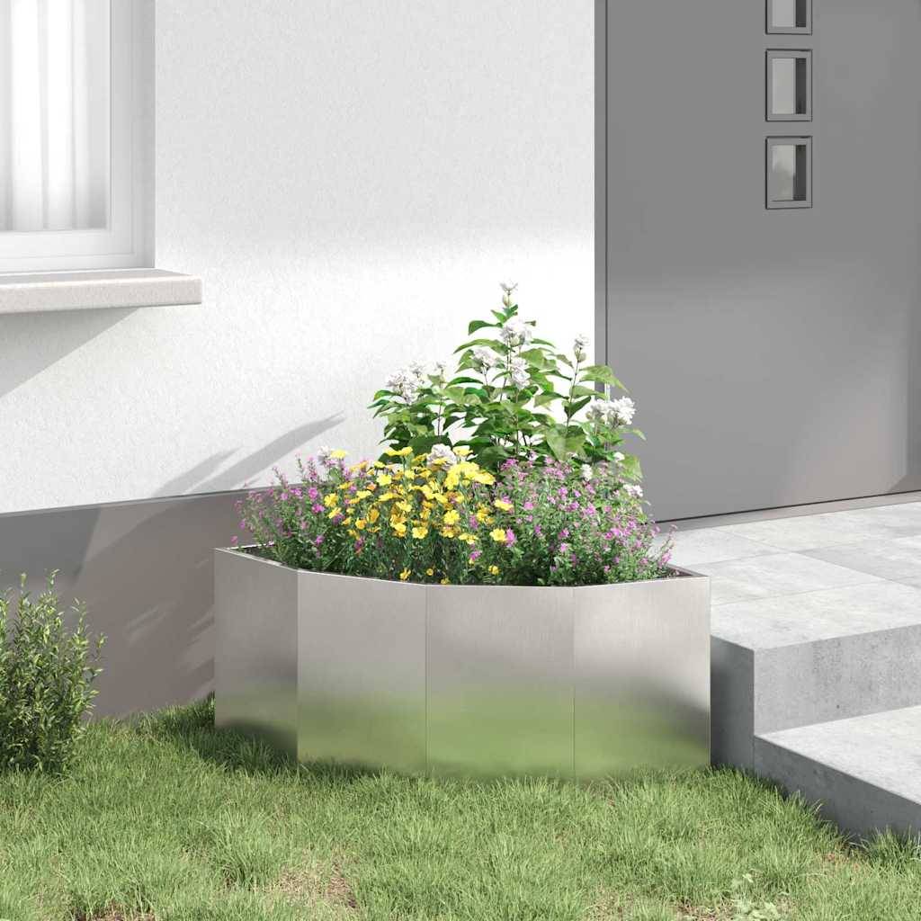 Ein kleiner Garten an einem modernen Hauseingang mit einer Mischung aus grünen, blattreichen Pflanzen und gelben Blumen, eingefasst von einem metallischen Pflanzgefäß.