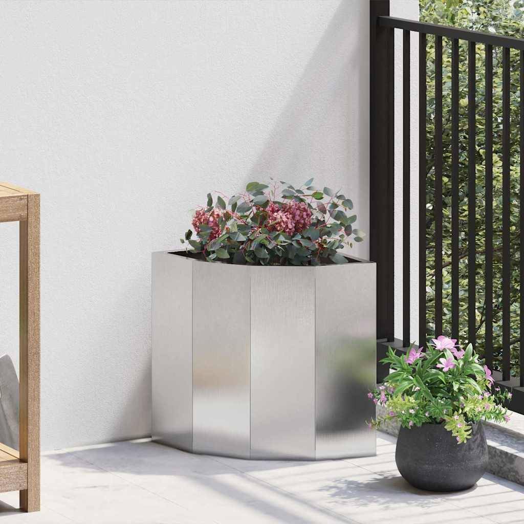 Eine moderne Terrasse im Freien mit Metallpflanzkübeln, die leuchtende Blumen tragen, neben einem Holzregal an einer weißen Wand.