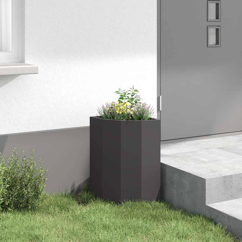 Eine moderne Gartenszene mit einem hohen, dunklen Pflanzgefäß mit Blumen neben einer Hauswand, einem Fenster, einem Türeingang und kleinen Stufen.