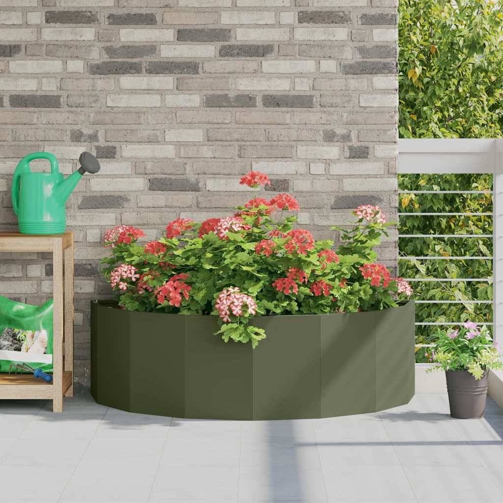 Ein Pflanzgefäß mit üppigen roten und rosa Blumen, das auf einer Terrasse mit einer Ziegelwand und einem Geländer platziert ist. Eine grüne Gießkanne steht auf einem nahegelegenen Regal.