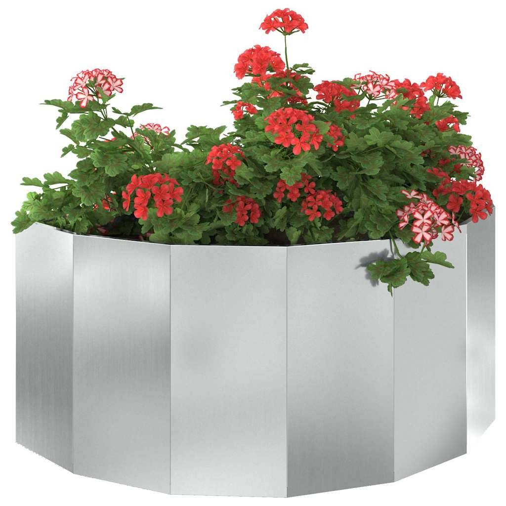 Ein sechseckiger Metallpflanzkübel, gefüllt mit leuchtend roten und rosa Blüten und üppigem grünem Blattwerk.
