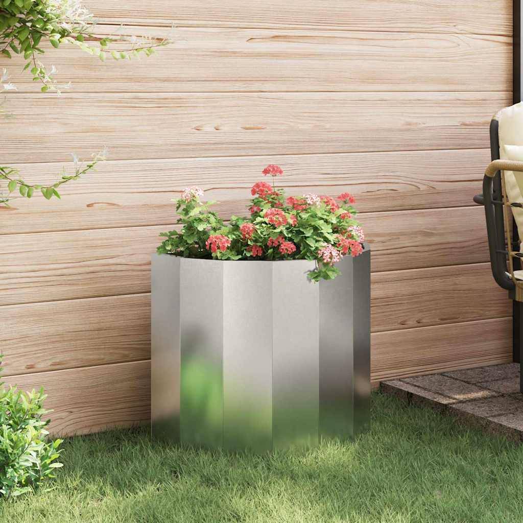 Ein moderner Metallpflanzer mit rosa und grünen Blumen wird vor einer Holzwand auf einem Rasengrund platziert und schafft eine friedvolle Gartenszene.