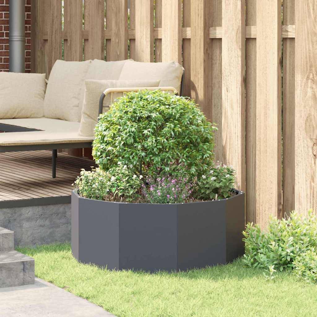 Eine gemütliche Terrasse mit einer gepolsterten Bank und einem runden Busch in einem Pflanzgefäß, umgeben von einem Holzzaun, schafft einen entspannten Außenbereich.