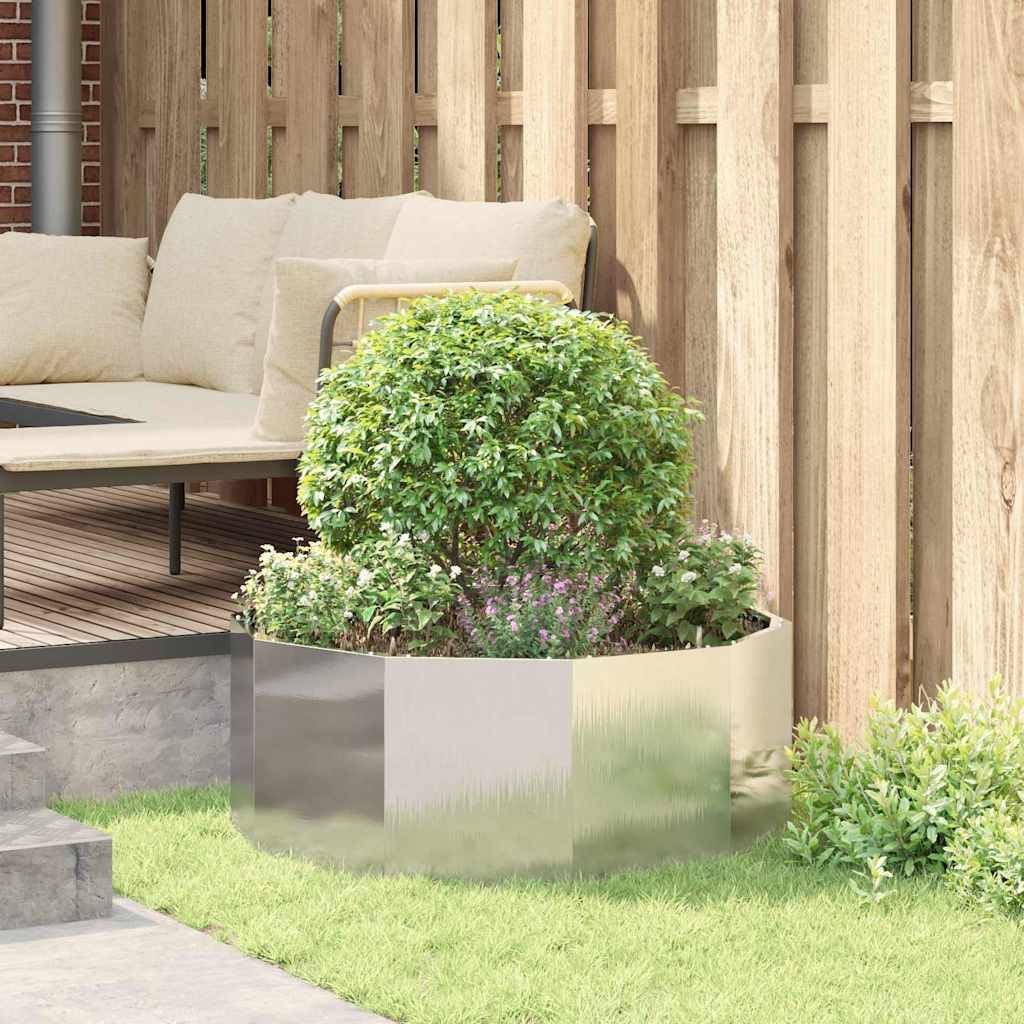 Eine moderne Terrasse präsentiert ein beiges Ecksofa mit Kissen, das sich neben einem polierten Metalltopf mit einem üppigen grünen Strauch befindet.