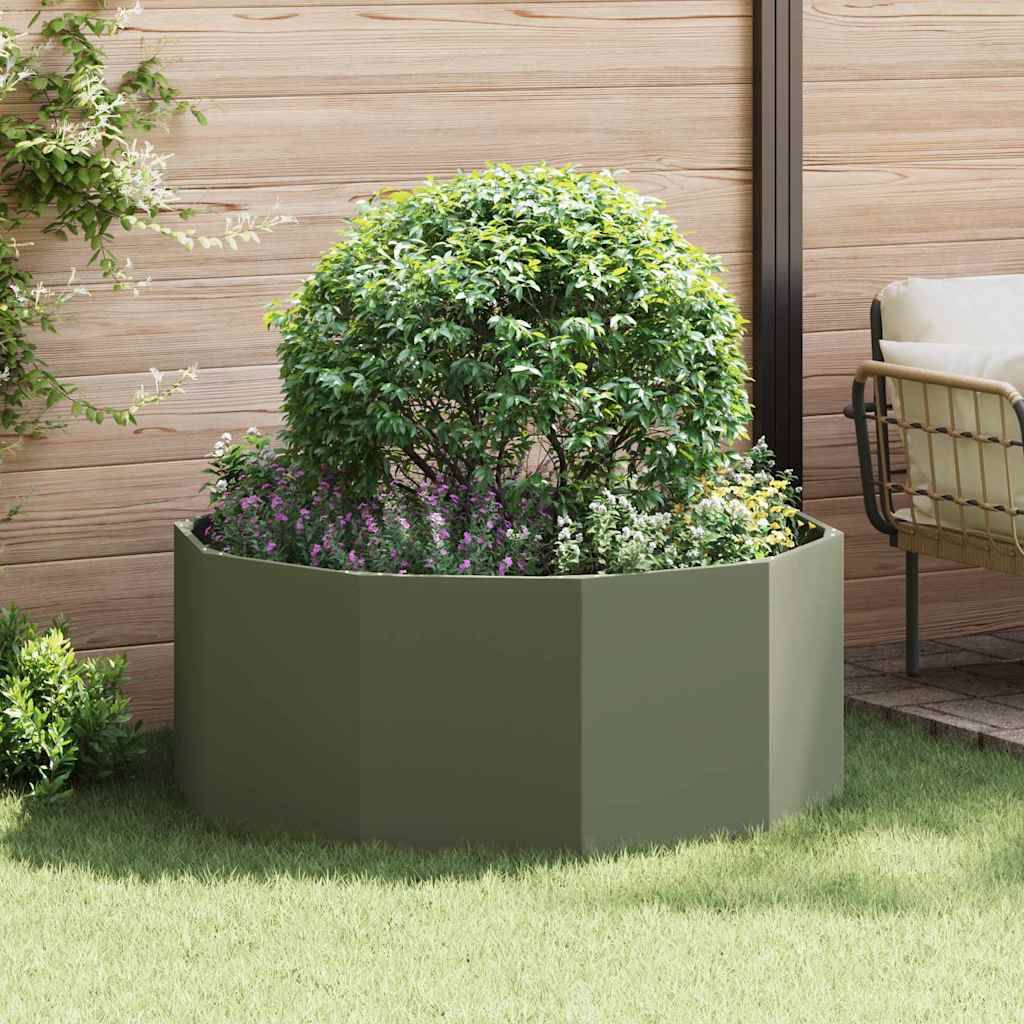 Ein üppiger grüner Busch in einem großen, runden, grauen Pflanzgefäß auf einer sonnenbeschienenen Terrasse mit Holzwänden und Gartenmöbeln in der Nähe.