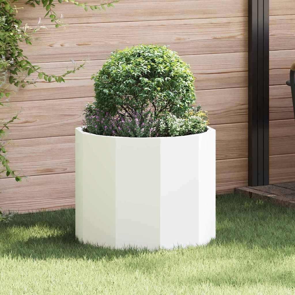 Ein runder weißer Pflanzgefäß enthält einen ordentlich geschnittenen grünen Strauch mit kleinen lila Blüten. Er steht vor einer Holzwand und Gras.
