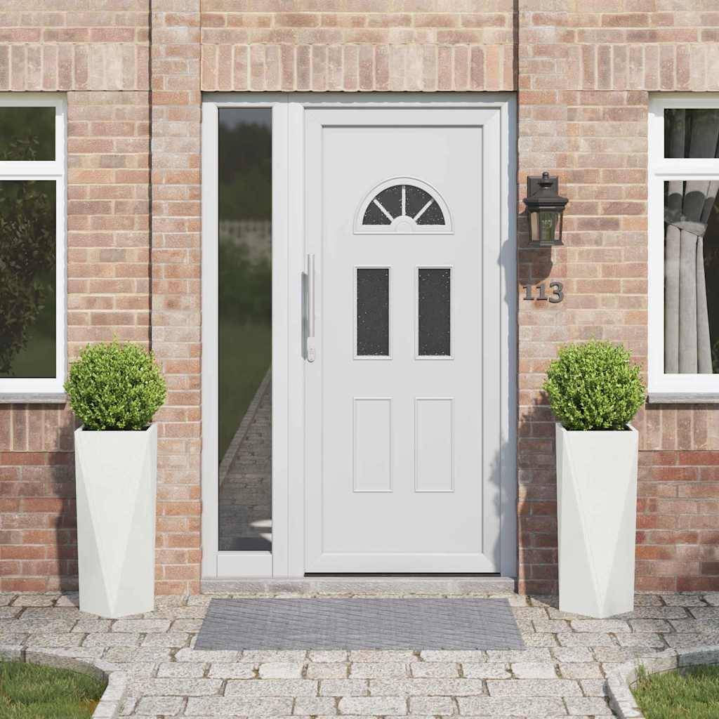 Eine weiße Haustür mit dekorativen Glaspaneelen ist mittig zwischen zwei Fenstern an einem Ziegelhaus positioniert. Zwei in Töpfen gezogene Sträucher flankieren den Eingang.