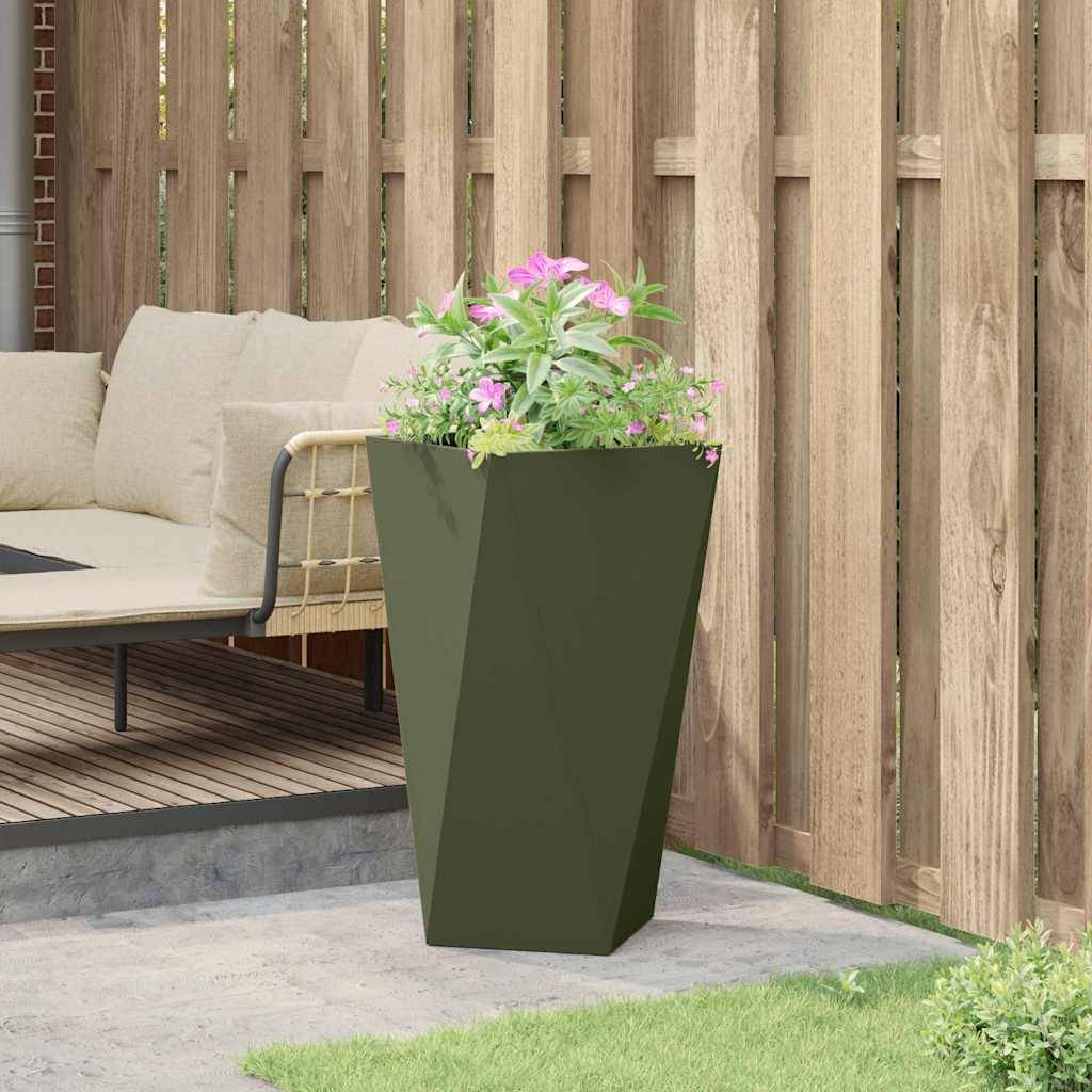 Eine moderne Terrasse mit einem beigen Ecksofa auf einer Holzterrasse, neben einem großen grünen Pflanzgefäß mit pinken Blumen, umgeben von einem Holzzaun.