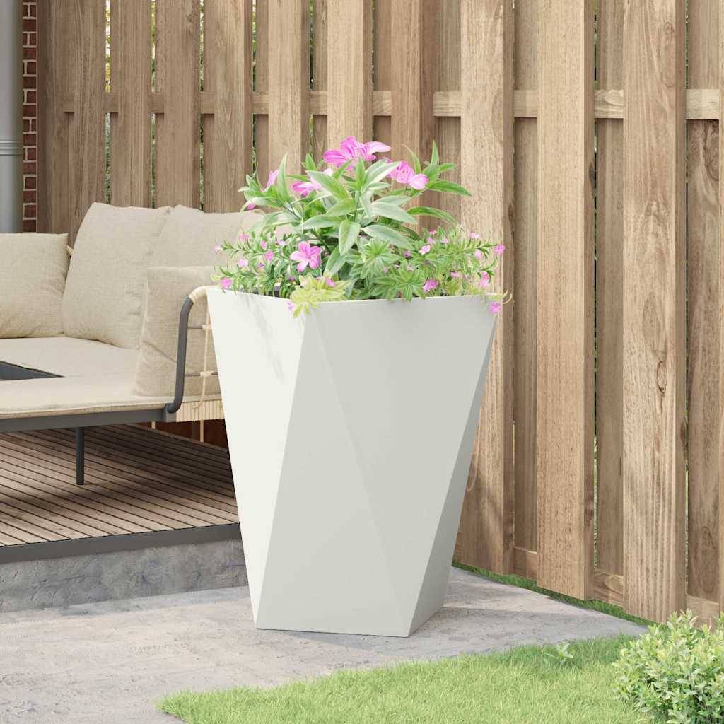Eine gemütliche Sitzecke im Freien mit einem beigen Sofa, einem Holzzaun als Sichtschutz und einem großen, weißen geometrischen Pflanzgefäß, gefüllt mit rosa Blumen.