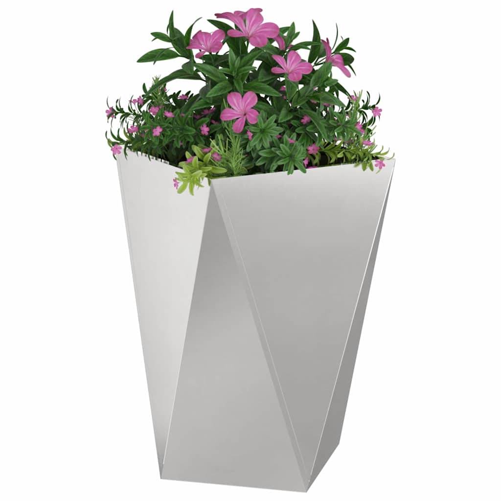 Ein geometrischer, eckiger weißer Pflanzentopf, gefüllt mit blühenden rosa Blumen und grünem Blattwerk, vor einem einfarbigen weißen Hintergrund.