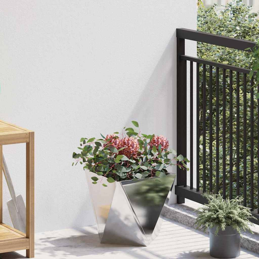 Eine moderne Balkonszene mit einem geometrischen Metallpflanzkübel, der pinke Blumen trägt, neben einem Holzregal und einem schwarzen Geländer, vor einer weißen Wand.