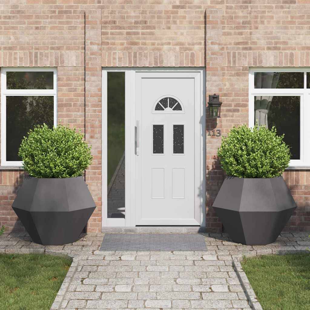 Eine Ziegelhausfassade mit einer weißen Tür, zwei symmetrischen Fenstern und zwei großen, grünen Kübelpflanzen, die den Eingangsweg flankieren.