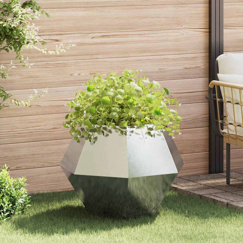 Ein großer geometrischer Pflanzkübel beherbergt üppige grüne Pflanzen auf einer Holzterrasse mit Holzverkleidung und weichen Grasflächen, was einen modernen Außenbereich andeutet.