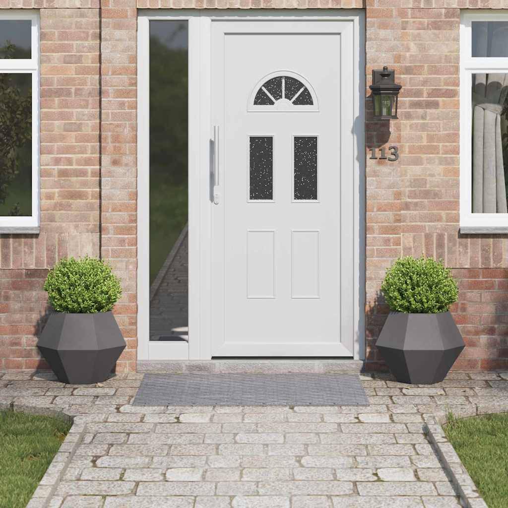 Eine weiße Haustür mit dekorativen Glaselementen ist in eine Ziegelhausfassade eingelassen. Zwei Topfpflanzen flankieren den Eingang.