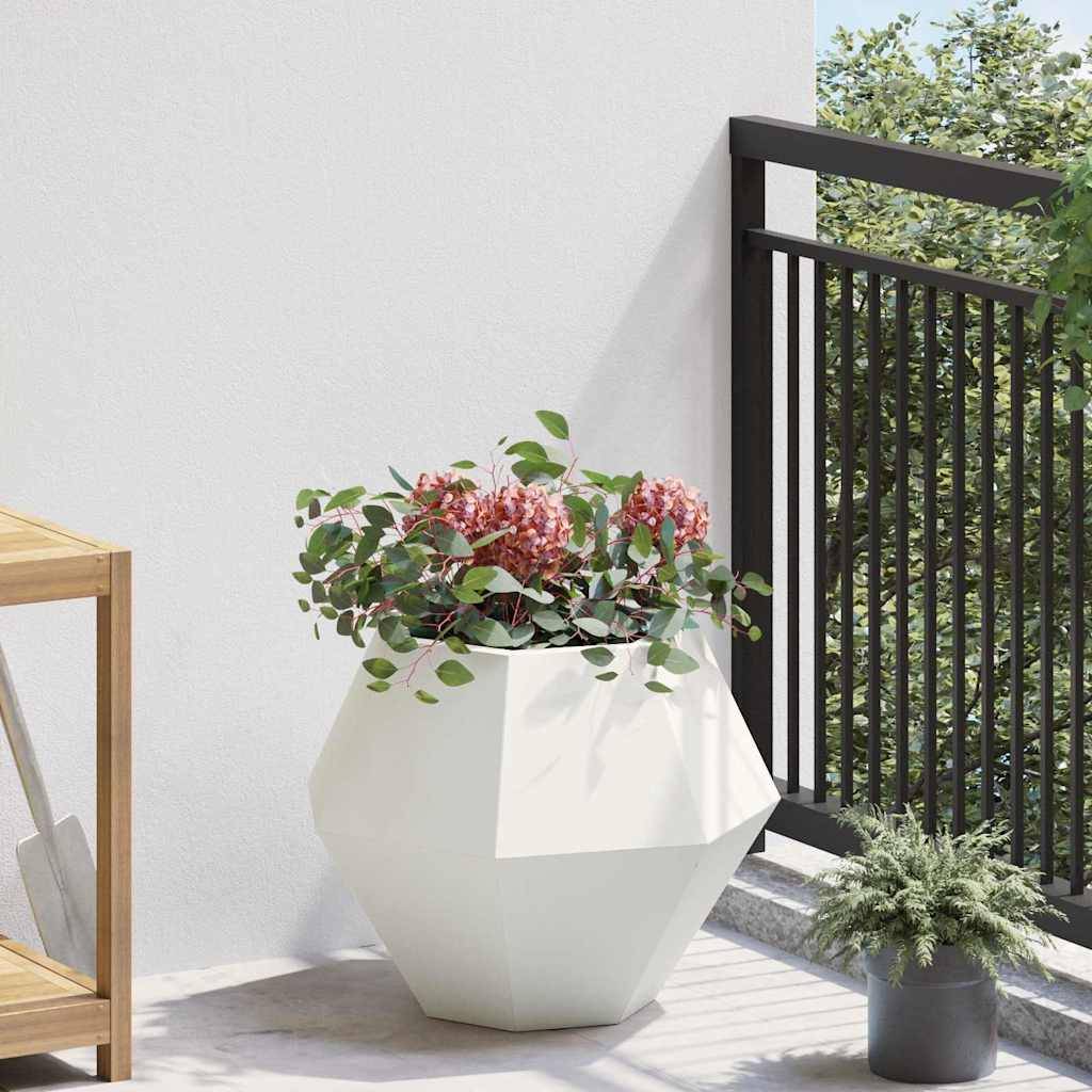 Ein weißer geometrischer Blumentopf mit leuchtend pinken Blumen steht auf einem sonnenbeschienenen Balkon neben einem dunklen Geländer, einem Holzregal und Grünpflanzen.