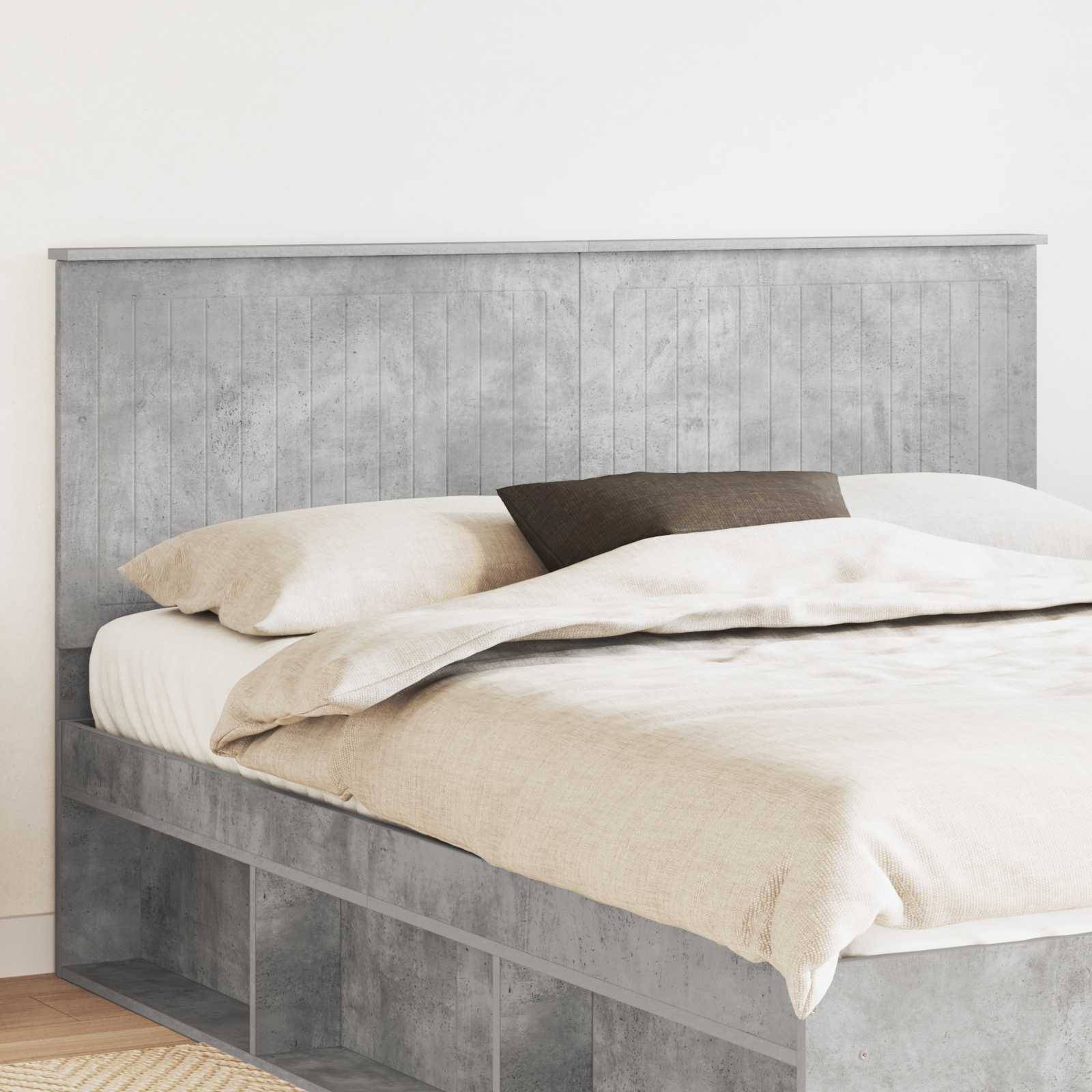 Ein ordentlich gemachtes Bett mit hellem Holzrahmen und Kopfteil, ausgestattet mit weißer Bettwäsche und zwei Kissen, steht in der Ecke eines hellen Zimmers.