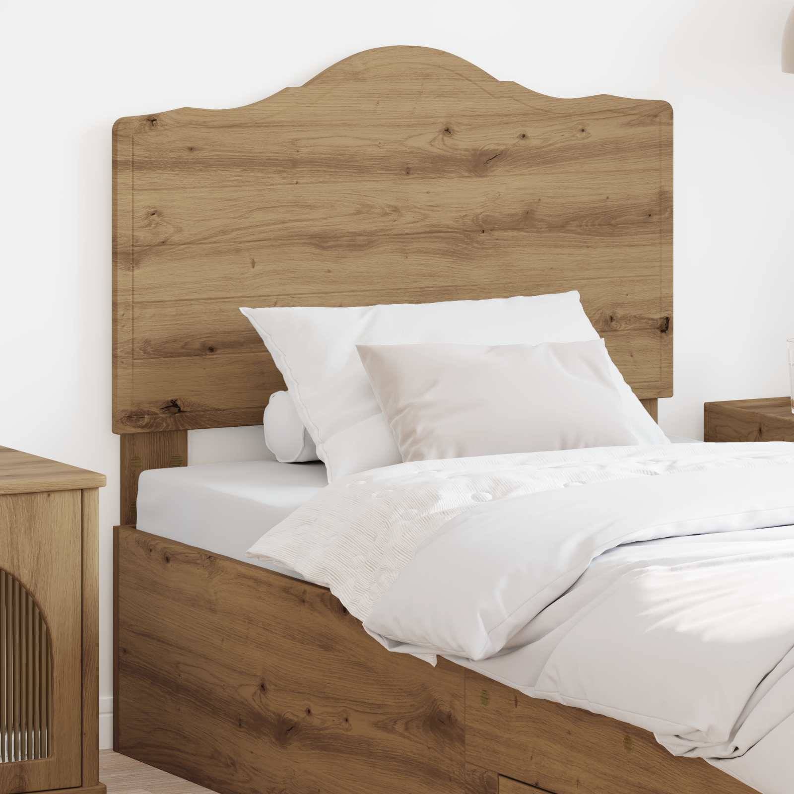Ein ordentlich gemachtes Bett mit einem Holzkopfteil und zwei weißen Kissen in einer einfachen, modernen Schlafzimmereinrichtung.