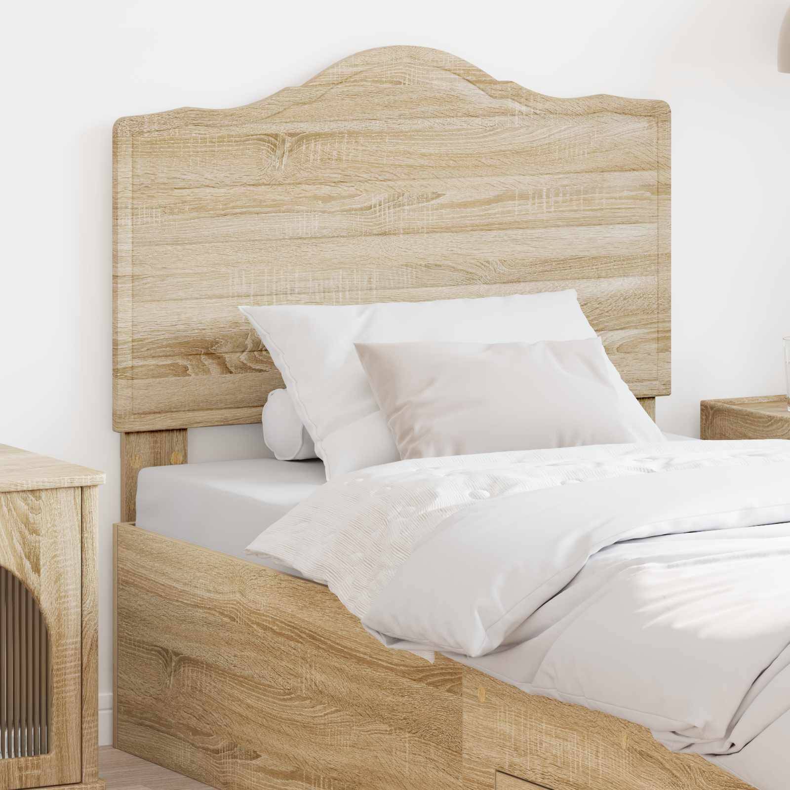 Ein ordentlich gemachtes Bett mit weißer Bettwäsche und einem hellen Holzkopfteil steht neben einem Nachttisch. Der Raum hat ein cleanes und minimalistisches Design.
