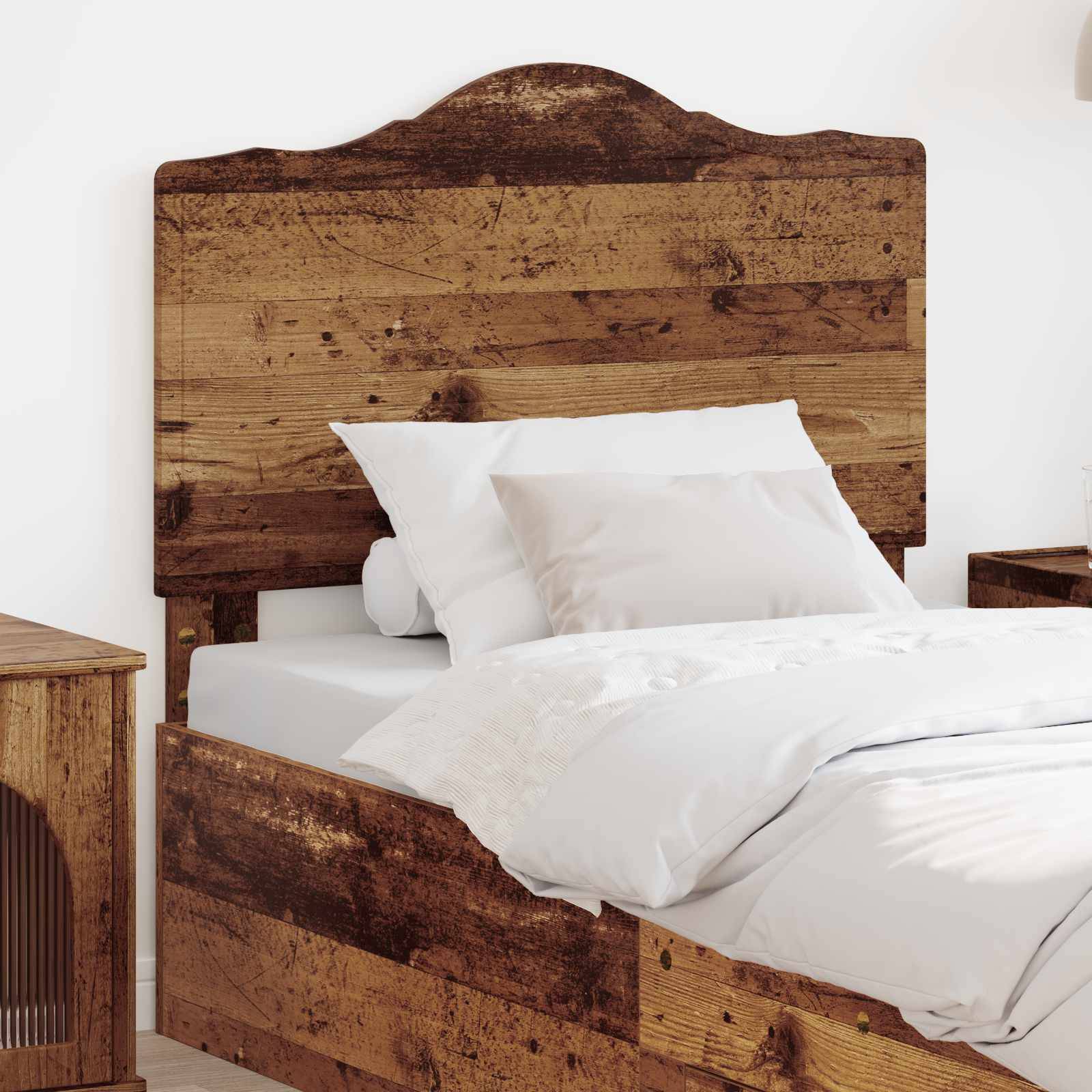Ein Holzbett mit rustikaler Oberfläche, ausgestattet mit weißen Kissen und Bettwäsche, befindet sich in einem hellen, minimalistischen Schlafzimmer.