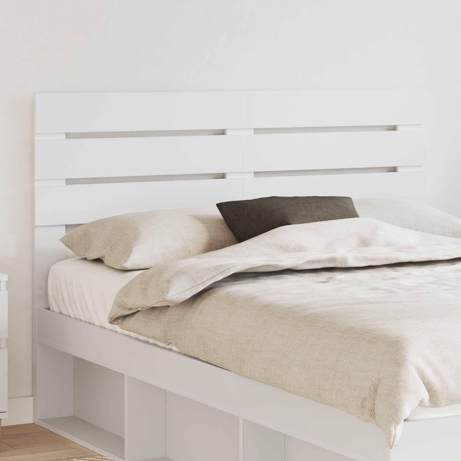 Modernes Schlafzimmer mit weißem Bett, Holzkopfteil, beigefarbener Bettwäsche und schwarzem Akzentkissen, das eine minimalistische und gemütliche Atmosphäre schafft.