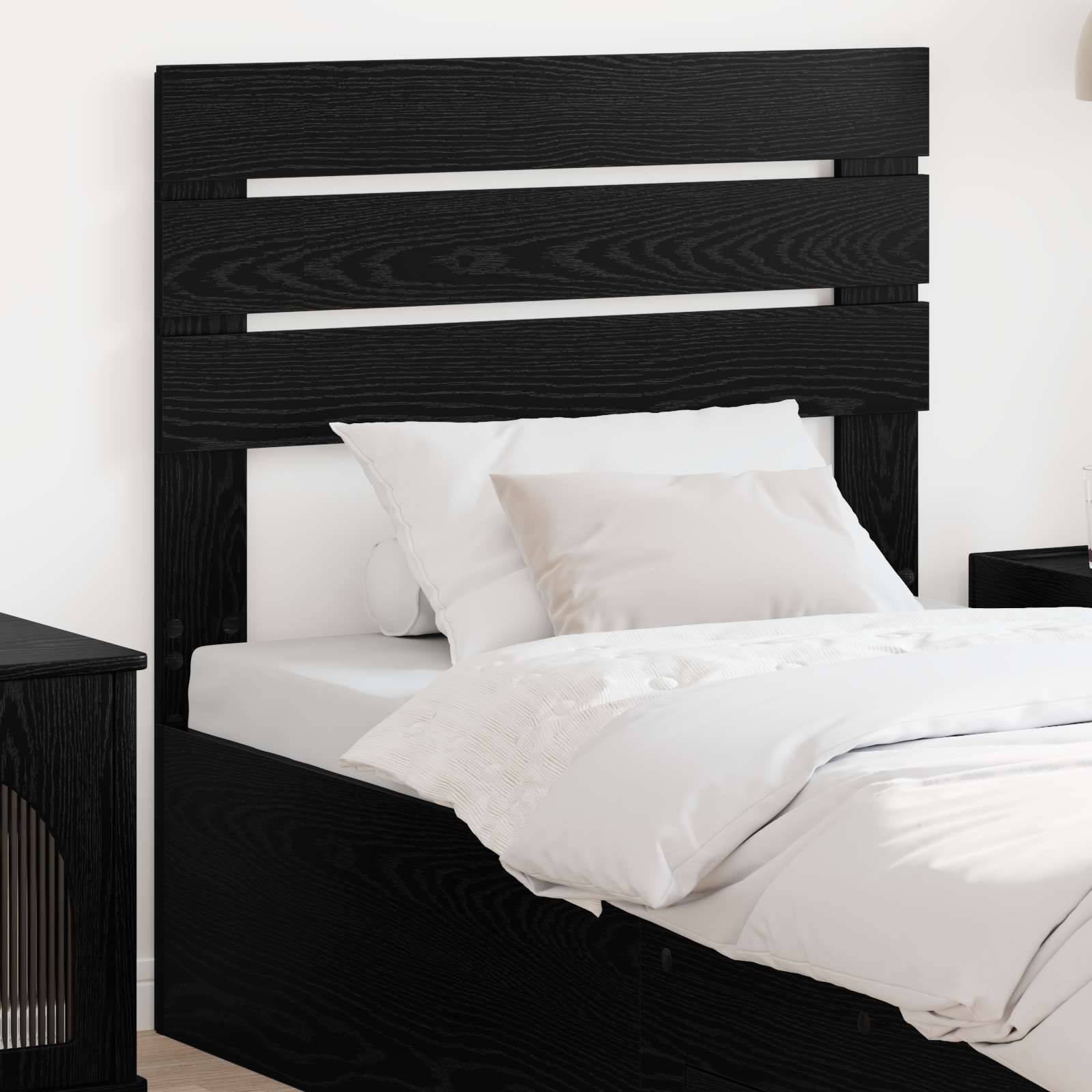 Ein modernes schwarzes Holzbett mit schlankem Kopfteil, verziert mit weißen Kissen und einer ordentlich angeordneten weißen Bettdecke, in einem minimalistischen Raum.