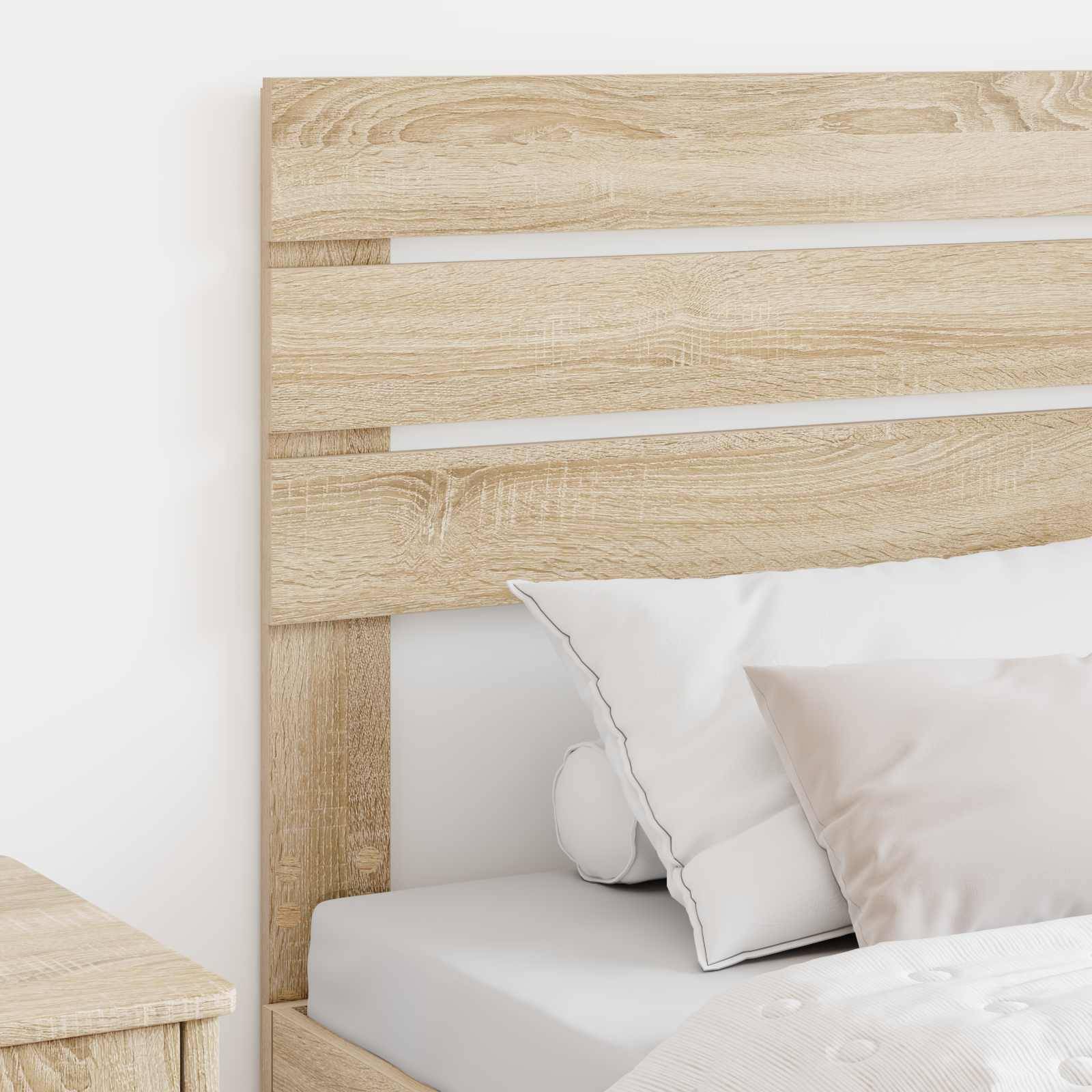 Ein Bettgestell aus hellem Holz mit weißer Bettwäsche und mehreren Kissen steht neben einem passenden Nachttisch und deutet auf eine moderne Schlafzimmereinrichtung hin.