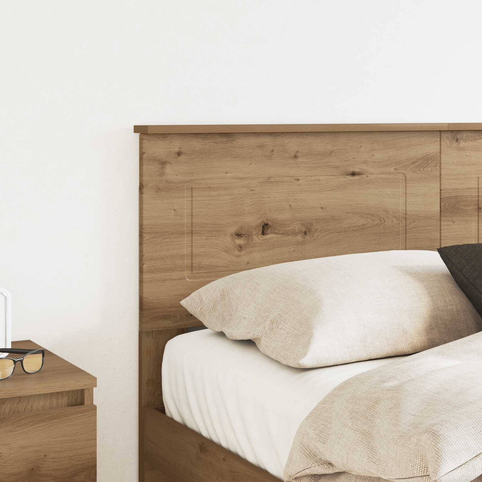 Ein ordentlich gemachtes Bett mit beige und weißer Bettwäsche an einem hölzernen Kopfende mit einem Nachttisch auf der linken Seite. Minimalistische Schlafzimmerdekoration.