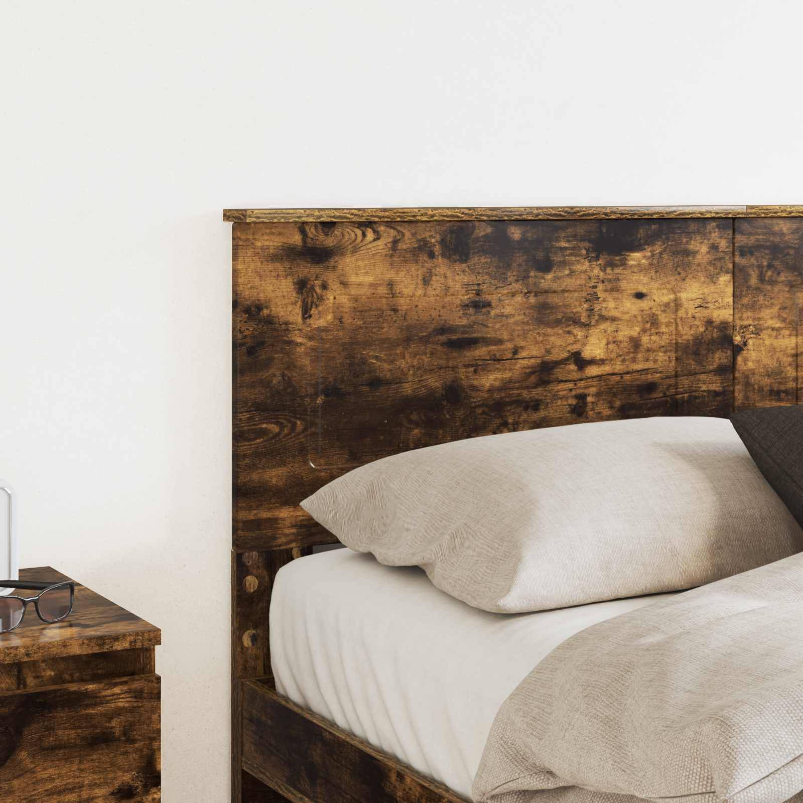 Ein rustikales Holzbett mit weißer Bettwäsche und Kissen gegen eine schlichte Wand, neben einem kleinen hölzernen Nachttisch.