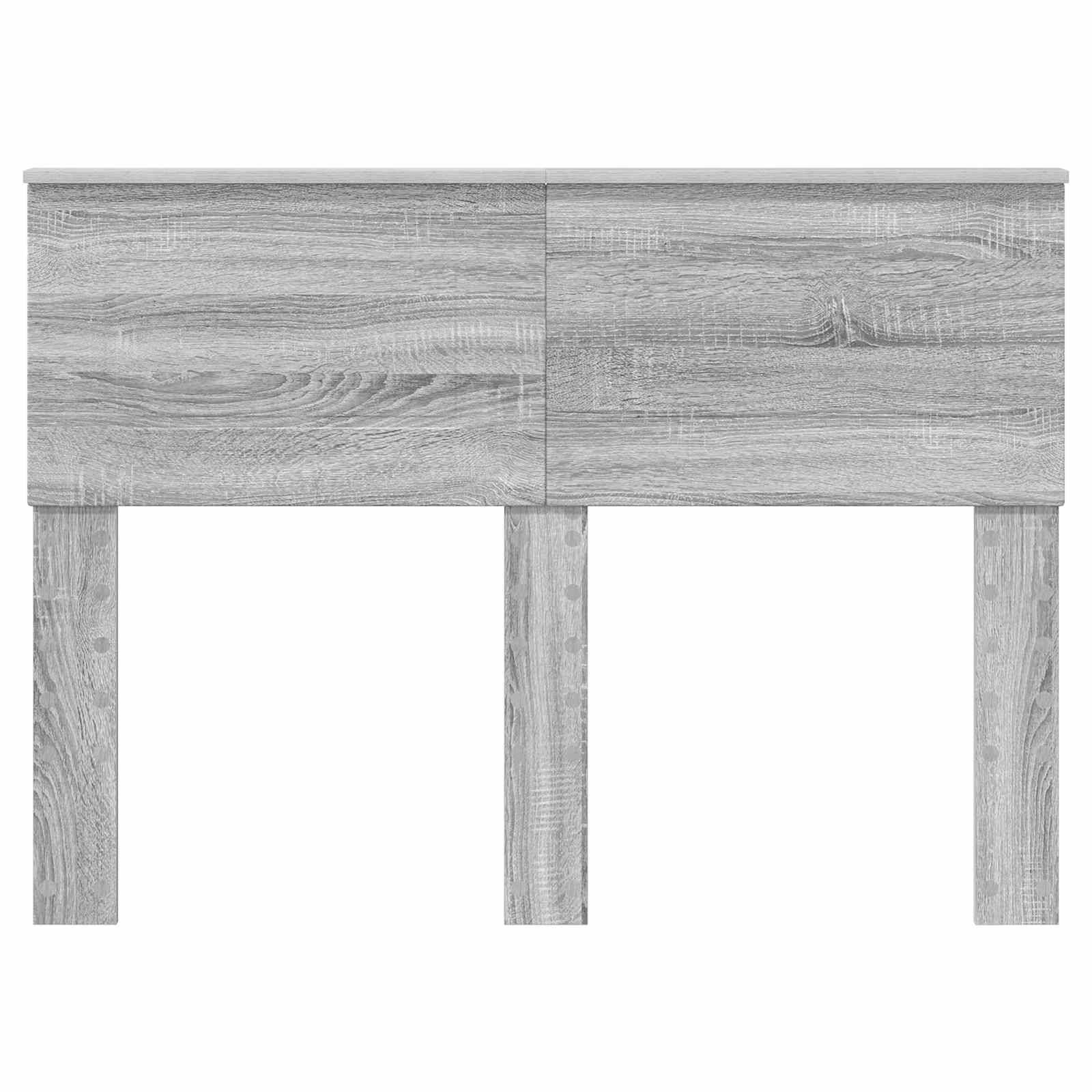Ein ordentlich gemachtes Bett mit hellen beigefarbenen Betttüchern und einem dunkelbraunen Kissen, angeordnet in einem Zimmer mit grauem Holzmöbel, einschließlich eines Kopfendes und eines Nachttisches.