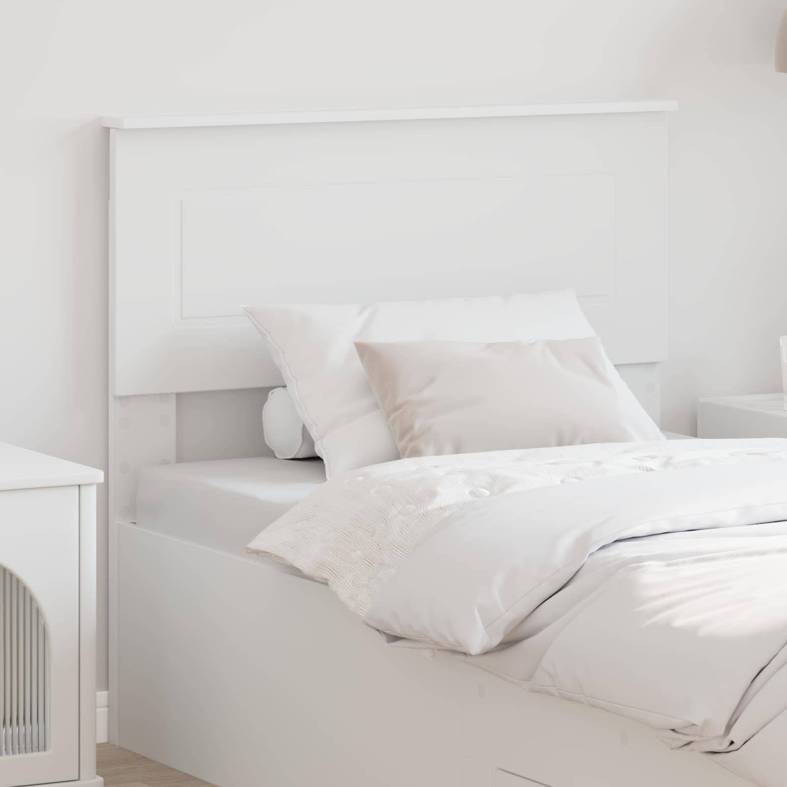 Ein ordentlich gemachtes Bett mit weißen Kissen und einer Bettdecke mit Blumenmuster in einem hellen, minimalistischen Schlafzimmer.