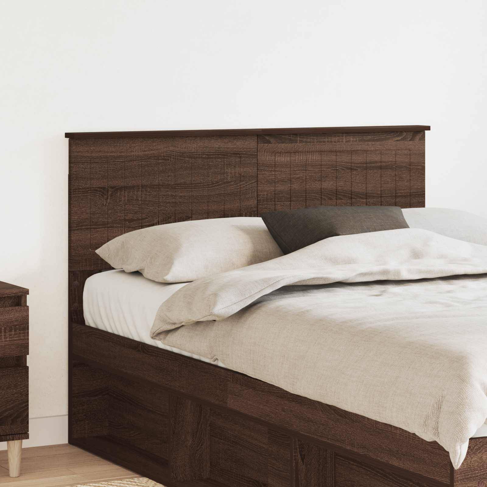 Ein ordentlich gemachtes Bett mit dunklem Holzkopfteil und neutraler Bettwäsche, positioniert neben einem kleinen passenden hölzernen Nachttisch.
