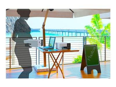 Eine Patio-Einrichtung mit einem Tisch, auf dem ein Laptop und ein Drucker stehen, und in der Nähe ein Kreidetafel-Schild mit der Aufschrift 