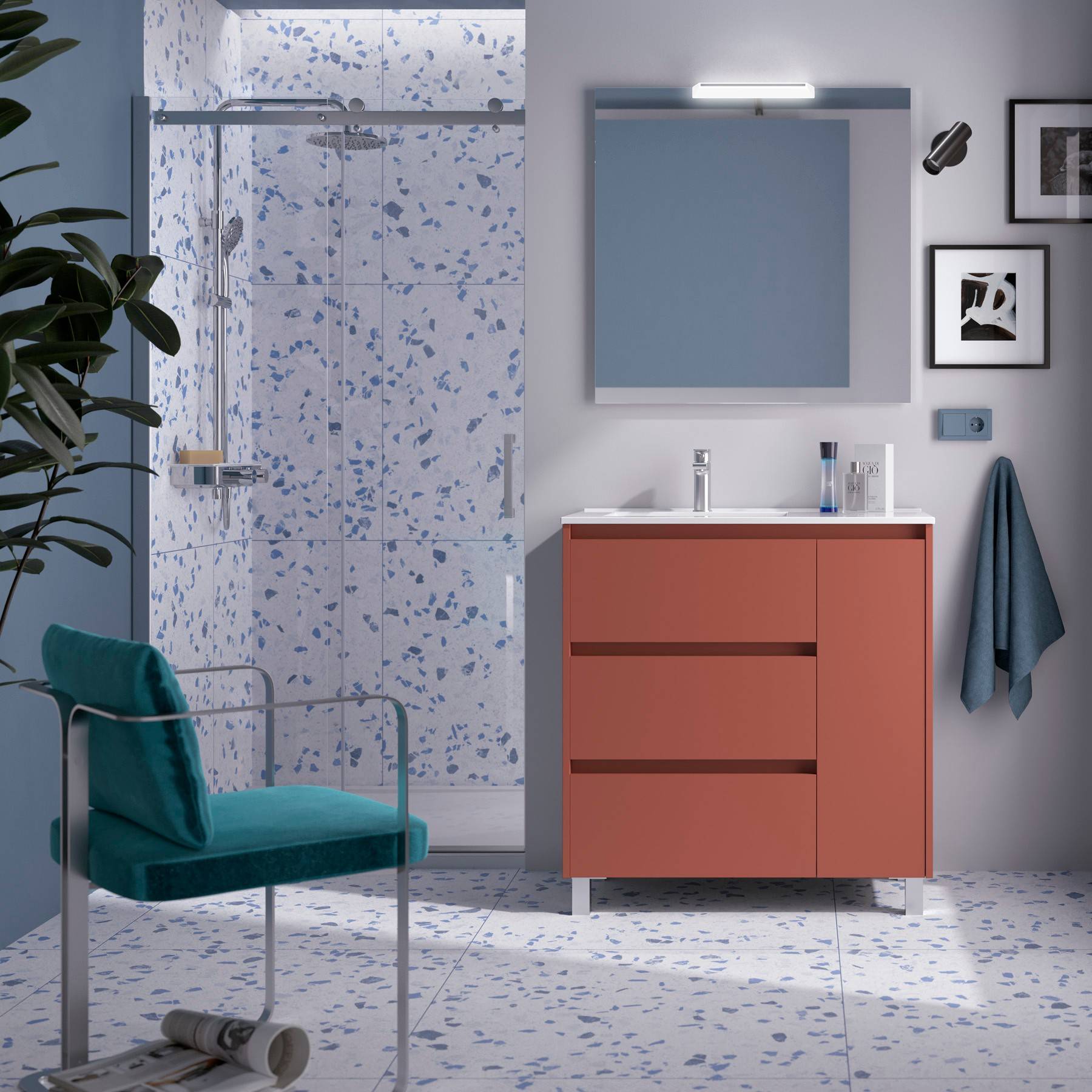 Modernes Badezimmer mit Glasdusche, blauen Terrazzoplatten, orangefarbener Waschtischplatte und petrolblauem Stuhl. Minimalistische Dekoration umfasst eine Pflanze und gerahmte Kunst.